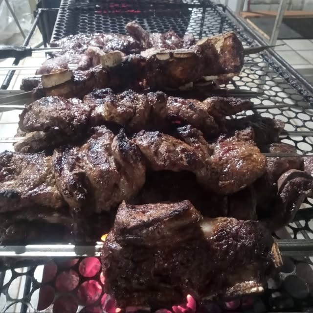 Churrasco nos espetos assando na brasa de carvão